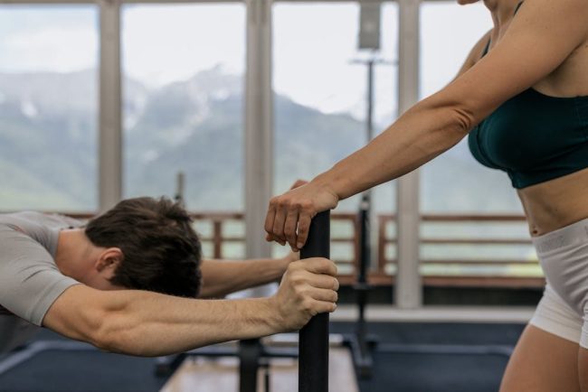 A couple working out together at an indoor gym with mountain views.
